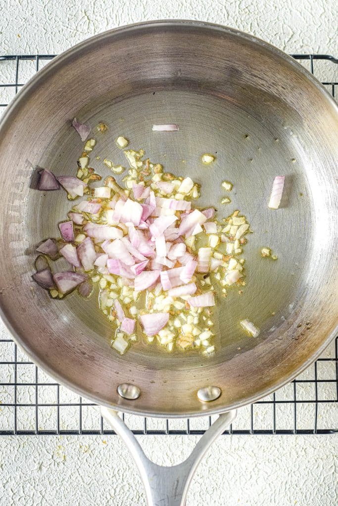 Sautéed chopped onions in a stainless steel pan on a cooling rack.